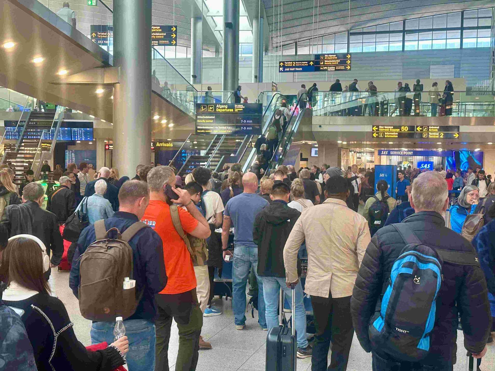 Travelers wait at a service counter at Copenhagen Airport